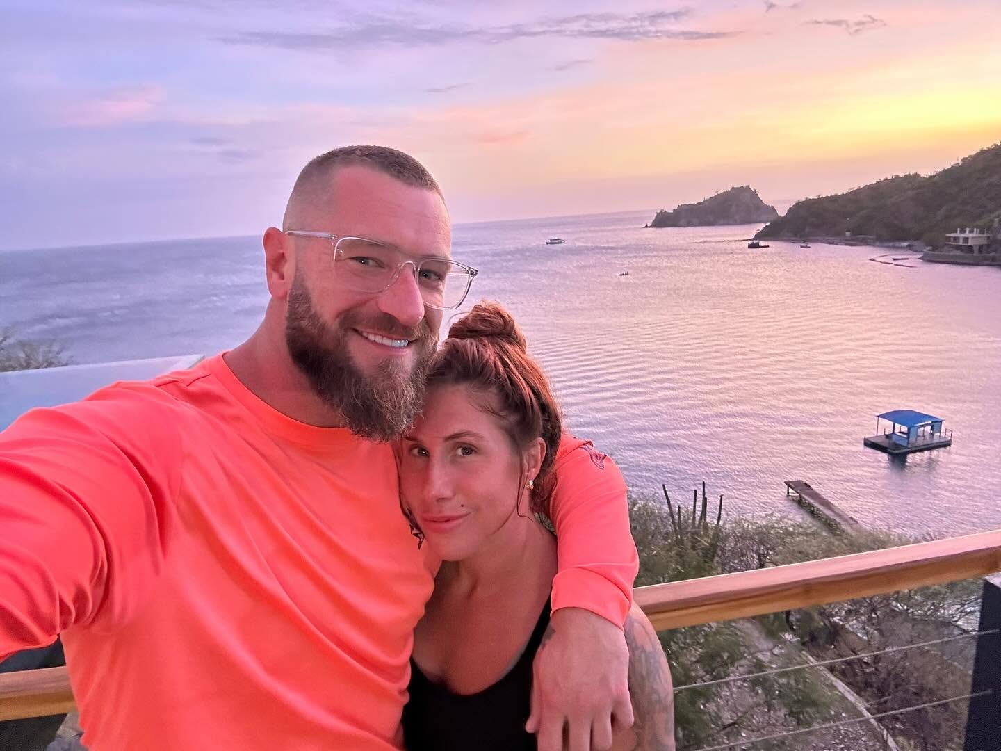 Coach and spouse overlooking a tropical bay at sunset
